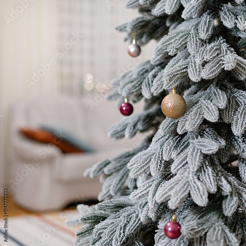 Decorated christmas tree with ornaments stands in a cozy living room