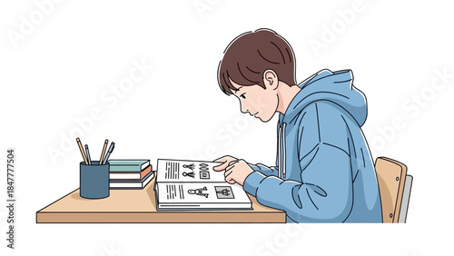 Young student studying diligently at wooden desk with books and pencils