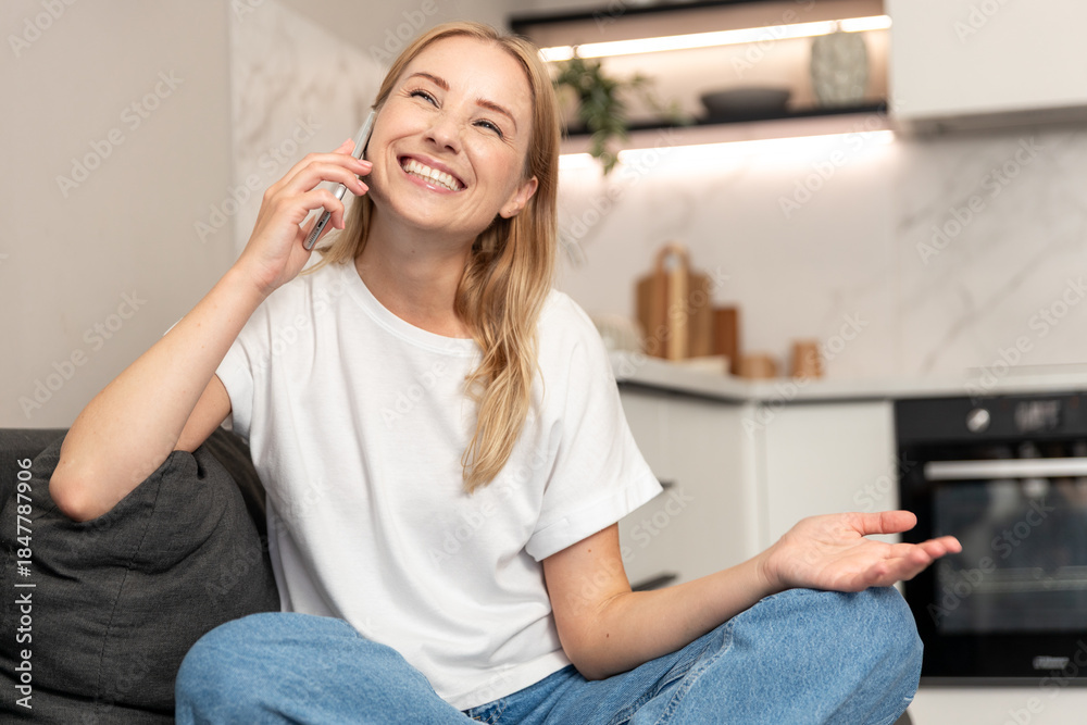 Fototapeta premium Woman enjoys a phone call while sitting in her modern apartment