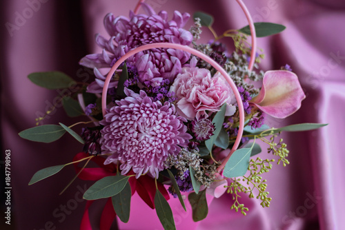 Floral arrangement with chrysanthemums, calla, carnations and eucalyptus in pink purple tones
