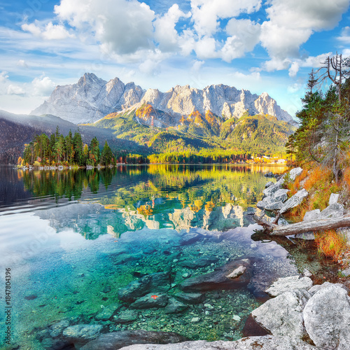 Amazing autumn landscape of Eibsee Lake in front of Zugspitze summit under sunlight.