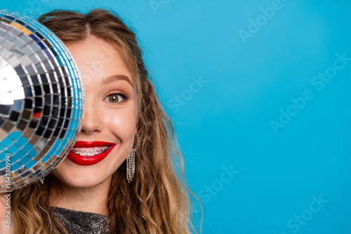 Fotografija Glamorous young woman with a disco ball in a bright blue studio showcasing party