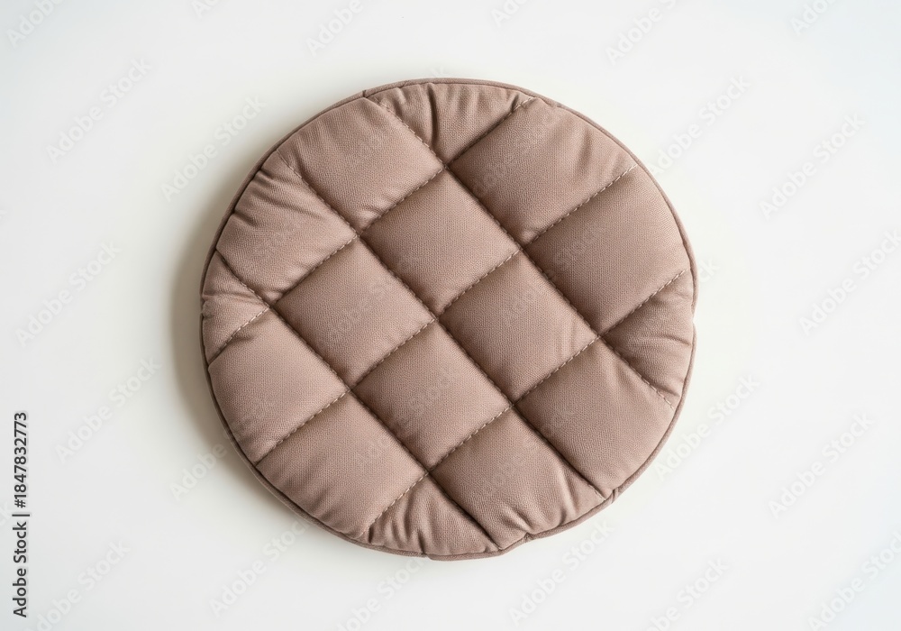 Naklejka premium Round quilted seat cushion rests centrally upon a plain white surface viewed from directly above.