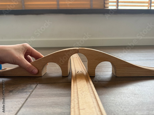 hand building toy bridge on wood floor, space for text, concept of education, toy store