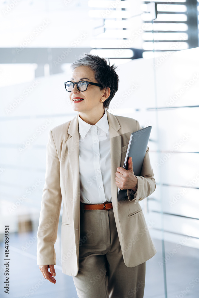 Fototapeta premium Elderly business woman walking in the hall of business center