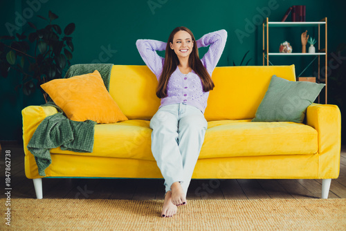 Tableau sur toile Young brunette woman relaxing on a bright yellow sofa in a stylish living room a