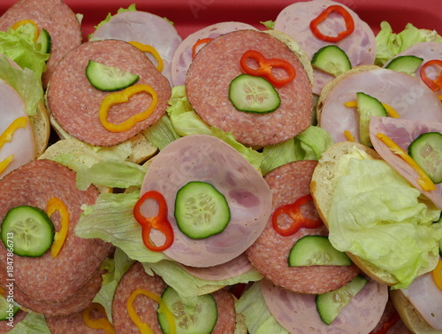 Sandwiches with sausage and cheese, garnished with cucumber and peppers – a popular savory snack for events and parties, perfect for any buffet.