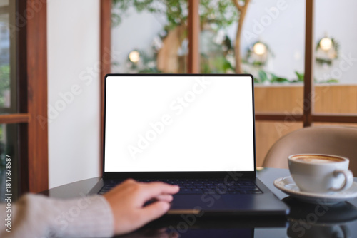 Mockup image of a woman working and typing on laptop computer with blank white desktop screen in cafe