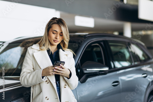 Woman in car showroom using mobile phone