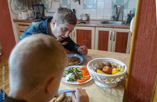 A man and his 9-year-old son eat together at the table