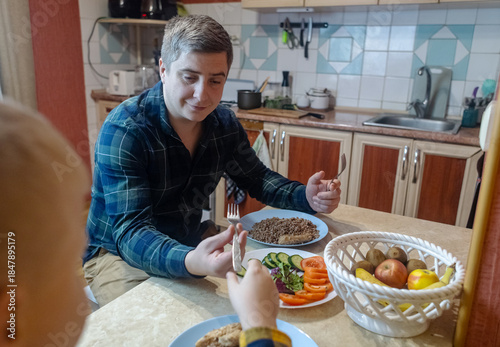 A man and his 9-year-old son eat together at the table