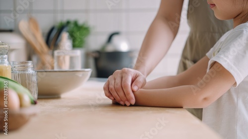 Adult guiding childs hands during quiet kitchen activity. Autism awareness concept highlighting parental support, learning through touch, routine and nurturing, inclusive family moment