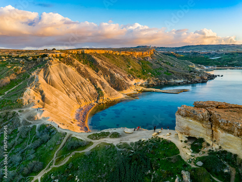 Drone sunset view of beach. Mediterranean sea, rocks, hills. Malta island