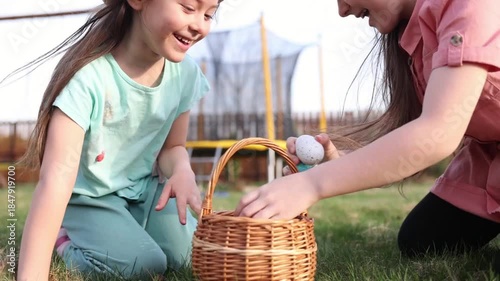 spring fun - finding eggs for easter outdoor in countryside. Happy children sitting on grass with found eggs and basket on sunny day. easter hunt in backyard.