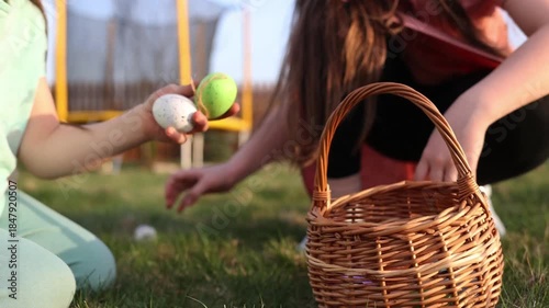 spring fun - finding eggs for easter outdoor in countryside. Happy children sitting on grass with found eggs and basket on sunny day. easter hunt in backyard.