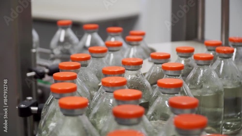 Pharmaceutical production line. Industrial Line Of Food, Medical Industry For Filling Liquids Into Bottles. Packing pallets with bottles filled with liquid and with red lids