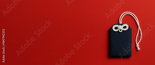 Japanese New Year omamori charm on red background, cultural decor with copy space