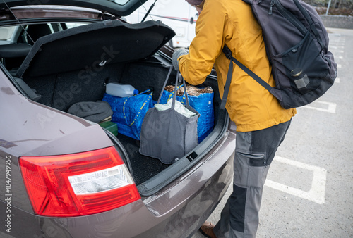 Bilde på lerret Person unloading reusable shopping bags from car trunk after grocery trip