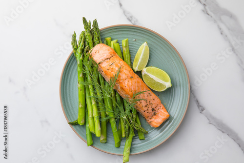 Healthy baked salmon served with roasted asparagus and seasonal vegetables on a plate. Clean eating, balanced nutrition, home cooking concept.