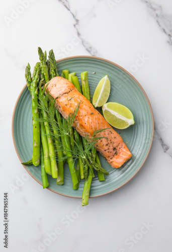 Healthy baked salmon served with roasted asparagus and seasonal vegetables on a plate. Clean eating, balanced nutrition, home cooking concept.