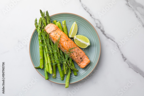 Healthy baked salmon served with roasted asparagus and seasonal vegetables on a plate. Clean eating, balanced nutrition, home cooking concept.