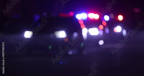 Abstracted illuminated night view of police units on a city street.