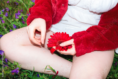 Woman Holding Red Flower Seated on Grass. Direct Flash