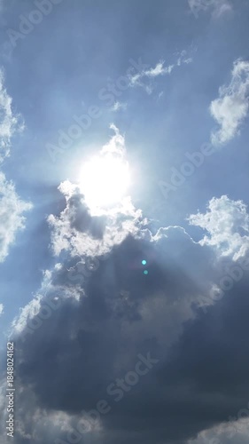 Aerial view of the afternoon sun and a slightly cloudy blue sky. Vertical video