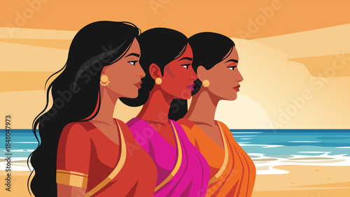 Three women in traditional Indian clothing standing on a beach at sunset.