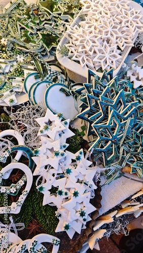 Handcrafted green and white ceramic Christmas ornaments in star and snowflake shapes displayed on a festive market stall. Concept of artisanal holiday charm, winter tradition