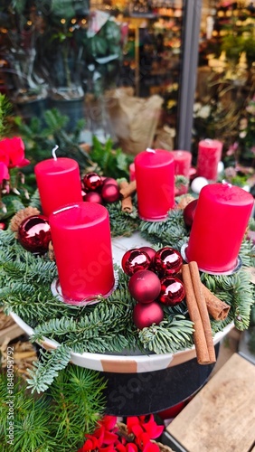 Christmas wreath with red candles, baubles, pine branches and cinnamon sticks arranged in a festive display. Concept of warm holiday tradition, Advent symbolism and cozy seasonal atmosphere