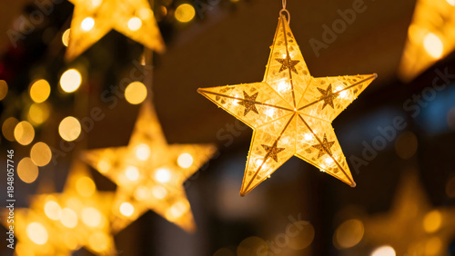 Close up of glowing star shaped lights hanging against a bokeh background.