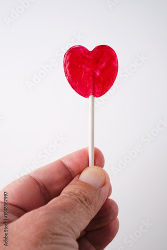 Holding a Red Heart Shaped Lollipop With a Stick in a Hand