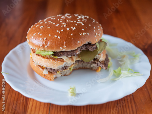 Delicious Half-Eaten Classic Double Cheeseburger on White Plate