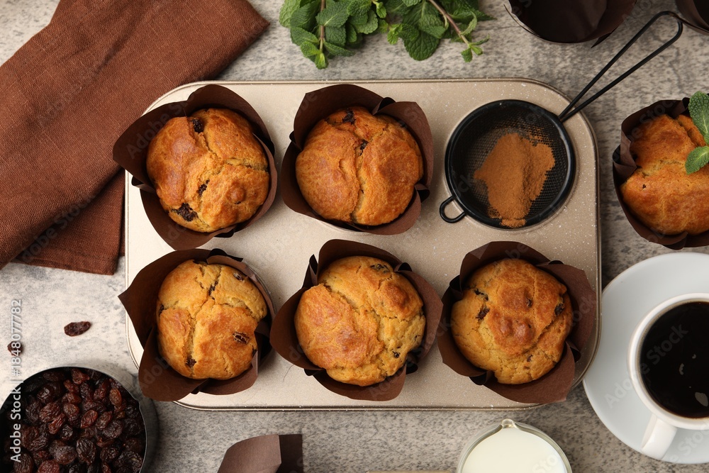 Naklejka premium Tasty muffins with raisins, mint and coffee on grey table, flay lay