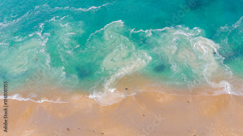 Aerial view of turquoise waves crashing onto the sandy shore of Hazards Beach, creating a mesmerizing dance of color and texture, Hazards Beach, Tasmania, Australia.
