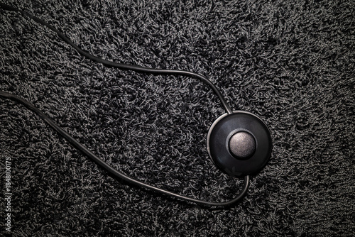 top view of a foot switch of a floor lamp on a long-pile carpet, all in black