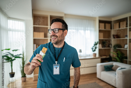 Foto Male nurse eating snack bar during break time