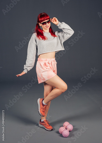 Beautiful happy redhaired woman with dumbbells showing energy, fitness and focus