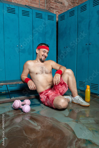 Cheerful man resting on the floor at the locker gym