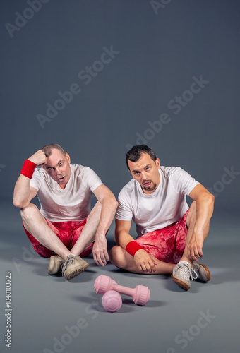 Two funny fitness men are resting after training