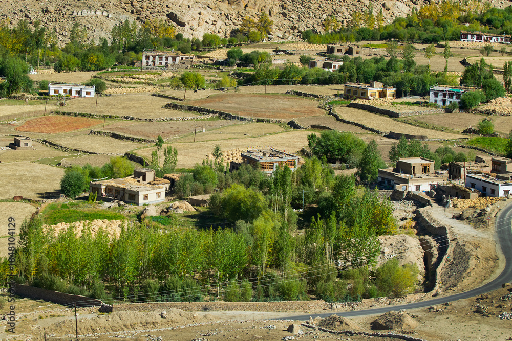 Fototapeta premium Chang La is a high mountain pass in Ladakh in Greater Himalaya between Leh and Shyok River valley. View of Himalayan agriculture and village below as seen from Chang La, on Leh to Pangong Lake road.