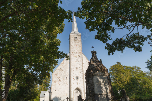 KADRINA, ESTONIA - AUGUST, 15, 2024: Church tower rising above green trees photographed on a clear summer day.