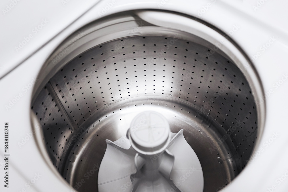 Obraz premium Empty washing machine drum interior. Stainless steel washer inside view. Clean laundry appliance. Modern household equipment. Minimal white design. Top view perspective. Domestic washing technology.