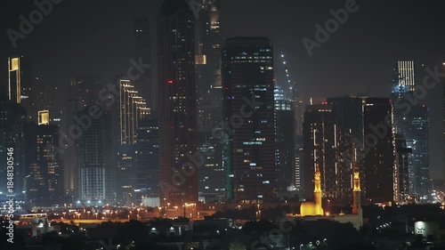 Panoramic view of Dubai at night showcasing modern skyscrapers and a beautifully lit mosque in the foreground