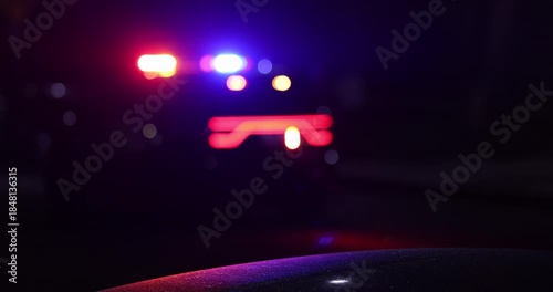 Abstracted illuminated night view of police units on a city street.