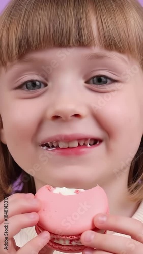 Little girl enjoys tasty pink macaron delight with sweet expressions