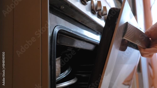 Close-up of a woman's hands opening the door of an electric oven,