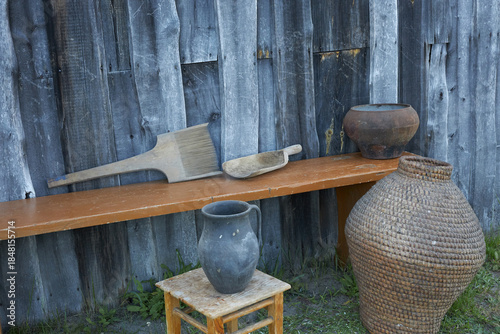 Objects of ancient village life near a wooden wall.