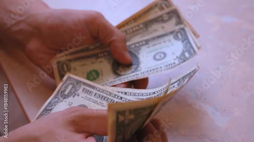 Male hands carefully counting one-dollar bills, a detailed close-up shot focused on the process of handling cash, representing financial transactions, savings, or economic activity